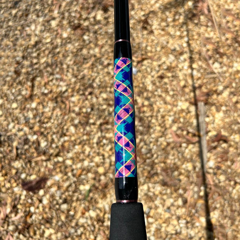 Load image into Gallery viewer, Built like our Fin #18, this spinning rod comes with Fuji alconite guides, EVA foam grips, Fuji reel seat, and metal gimble. Partial black foam grip showing. Side view of butt diamond pattern butt wrap. Yellow, blue, pink, teal butt wrap colors. Metallic pink trims/
