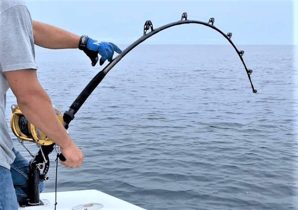 Load image into Gallery viewer, T-10x Adjusta-butt in black shown in action on the water. With a Penn 130 class reel in gold, and a 130 class all black rod. 
